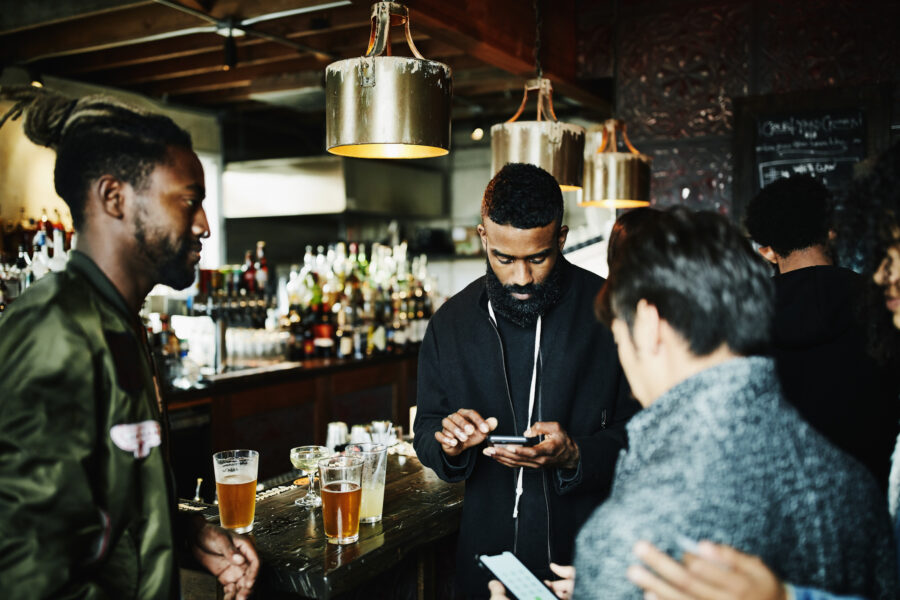 Friends exchanging contact information on smart phones while hanging out in bar