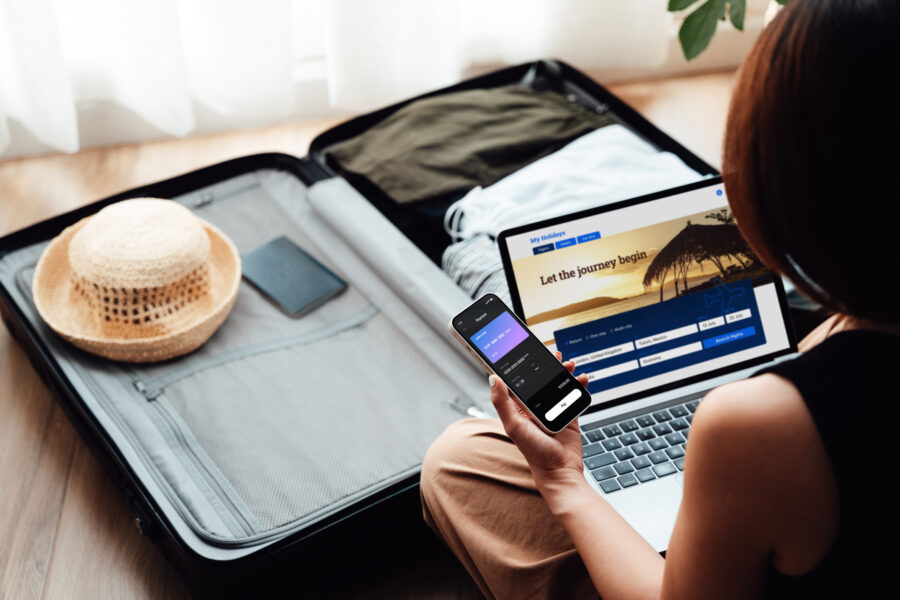 Young woman booking flight and hotel online with laptop and smartphone. Business and leisure travel.