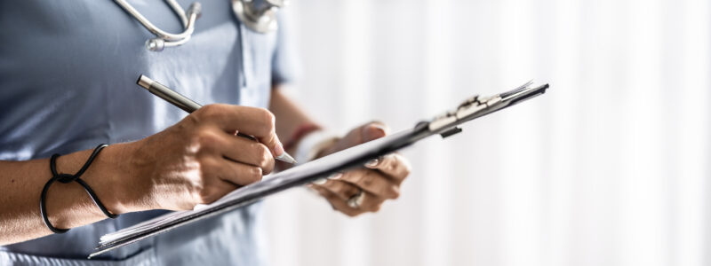 Female doctor filling up medical form on clipboard closeup. Healthcare, insurance and medicine concept.