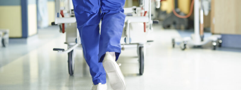 Legs of medic running with gurney along hospital corridor